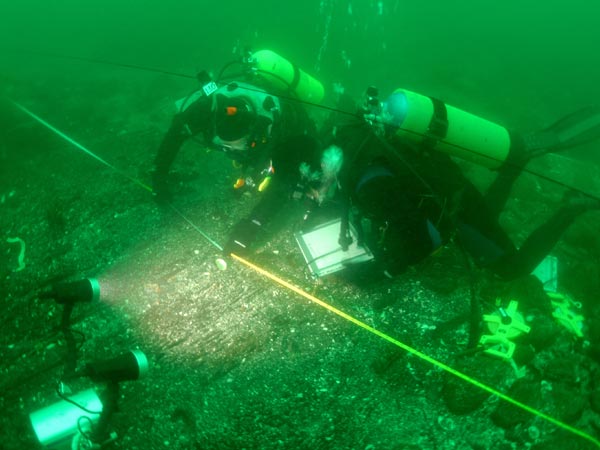 Archaeologists, working in 47 degree water, carefully draw the timbers used to build the ship's the lower hull.