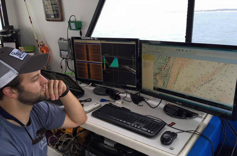 A survey technician observes the acoustic survey data and navigation information.